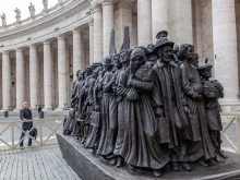 Canadian sculptor Timothy P. Schmalz poses next to his sculpture on the theme of refugees and migration, “Angels Unawares,” in St. Peter’s Square at the Vatican.