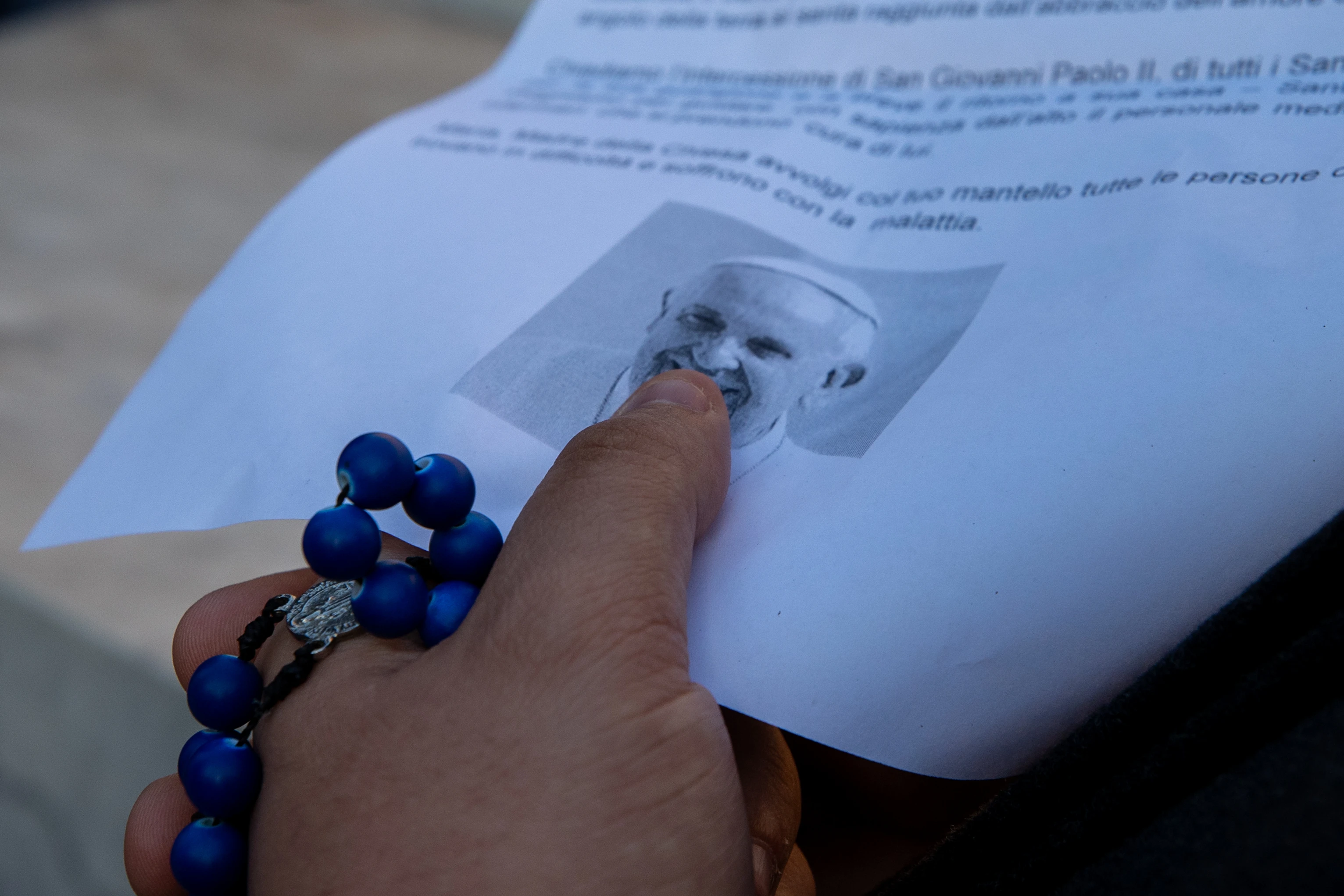 A faithful holds a rosary while touching an image of Pope Francis during prayers for the pontiff's recovery at Gemelli Hospital in Rome on Saturday, Feb. 22, 2025. | Credit: Daniel Ibáñez/CNA