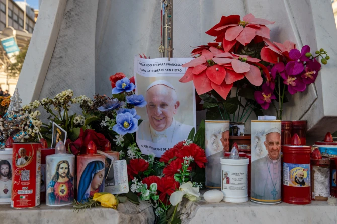 A makeshift shrine with devotional candles, flowers, and images of Pope Francis appears outside Rome's Gemelli hospital on Feb. 22, 2025