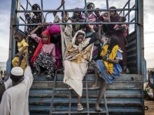 Sudanese refugees who have fled from the war in Sudan get off a truck loaded with families arriving at a transit center for refugees on Feb. 13, 2024.