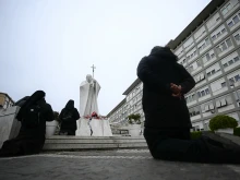 People pray at the statue of John Paul II outside the Gemelli Hospital, where Pope Francis is hospitalized with pneumonia, in Rome on Feb. 26, 2025.