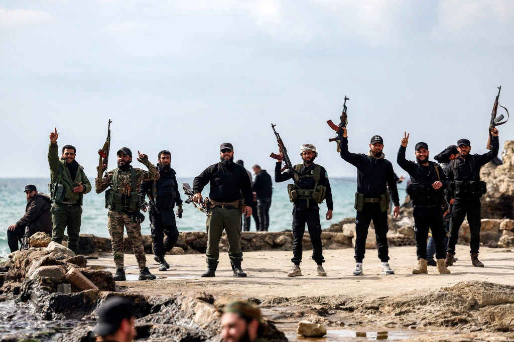Members of security forces loyal to the interim Syrian government hold up their firearms as they stand by the Mediterranean sea coast in Syria’s western city of Latakia on March 9, 2025. Syria’s interim president, Ahmed al-Sharaa, called for national unity and peace on March 9 amid growing international backlash following the killing of civilians along the country’s coast in the worst violence since the overthrow of former president Bashar al-Assad in the heartland of the Alawite minority, to which the latter belongs.?w=200&h=150