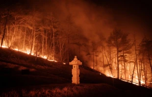 A wildfire blazes next to a stone lantern of family tomb in Andong, South Korea, on March 26, 2025. At least 18 people have been killed in one of South Korea’s worst wildfire outbreaks, with multiple blazes burning and causing “unprecedented damage,” the acting president said. Credit: YASUYOSHI CHIBA/AFP via Getty Images