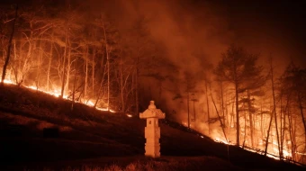 A wildfire blazes next to a stone lantern of family tomb in Andong, South Korea, on March 26, 2025. At least 18 people have been killed in one of South Korea’s worst wildfire outbreaks, with multiple blazes burning and causing “unprecedented damage,” the acting president said.
