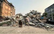 People stand past the debris of a collapsed building in Mandalay, Myanmar, on March 28, 2025, after a powerful earthquake killed more than 150 people across Myanmar and Thailand on March 28, toppling buildings and bridges and trapping over 80 workers in an under-construction skyscraper in Bangkok.