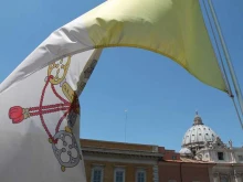 A Vatican flag waves over the dome of St. Peter’s Basilica.